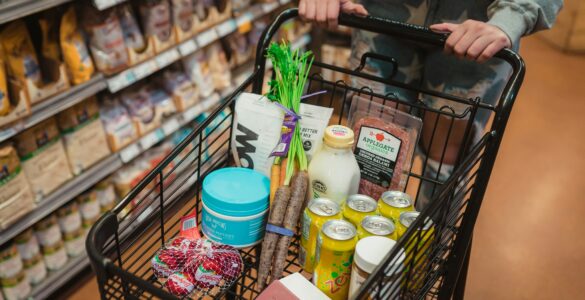 A shopper pushing a grocery cart filled with food in a supermarket aisle
