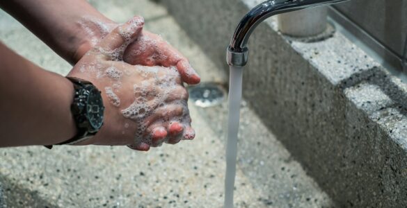 Hands covered with soap being washed under running water at a sink