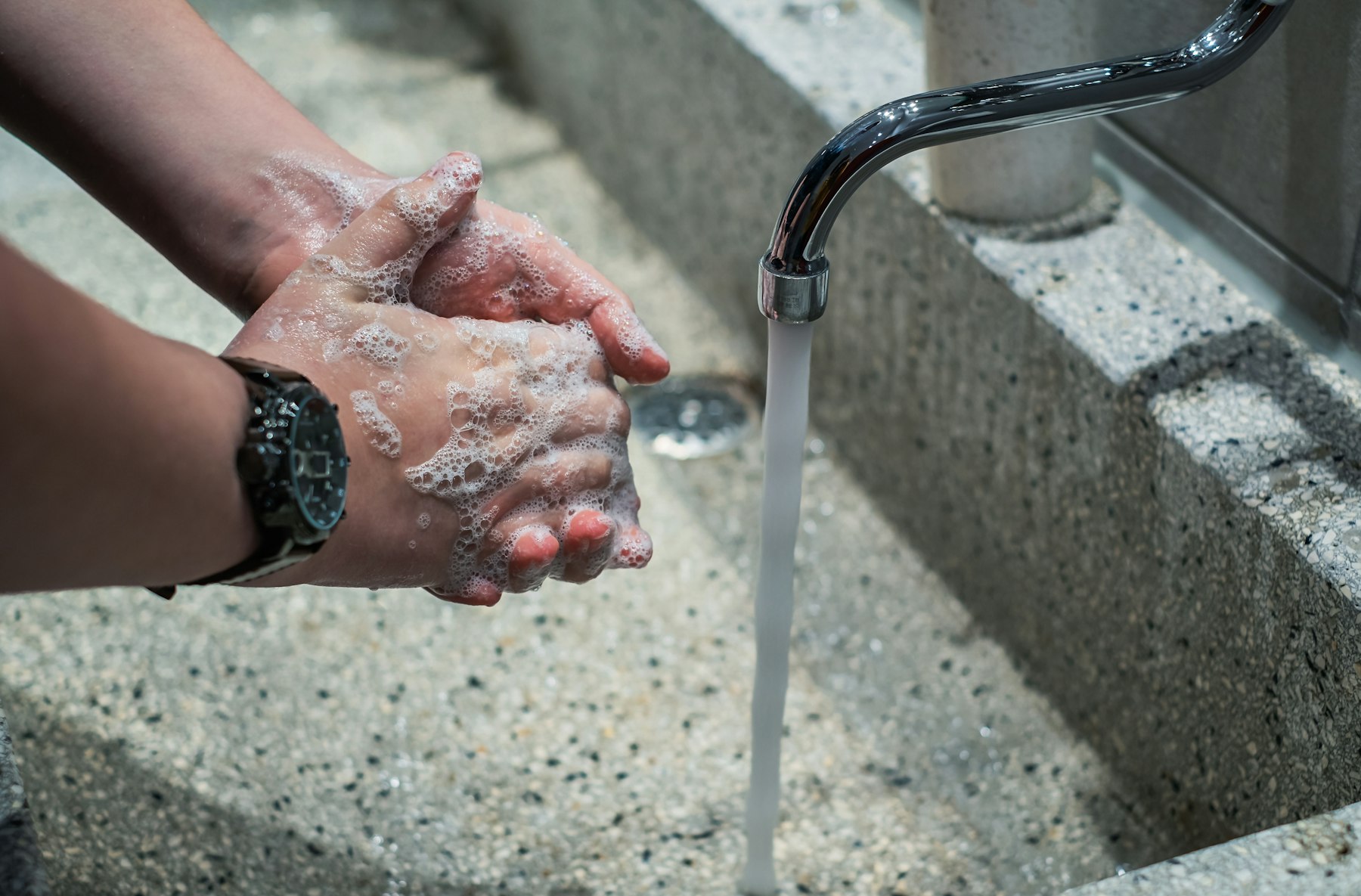 Hands being washed with soap under running water during a water safety precaution