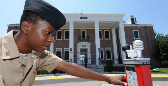 A person checks a wet bulb globe temperature meter during hot outdoor conditions.