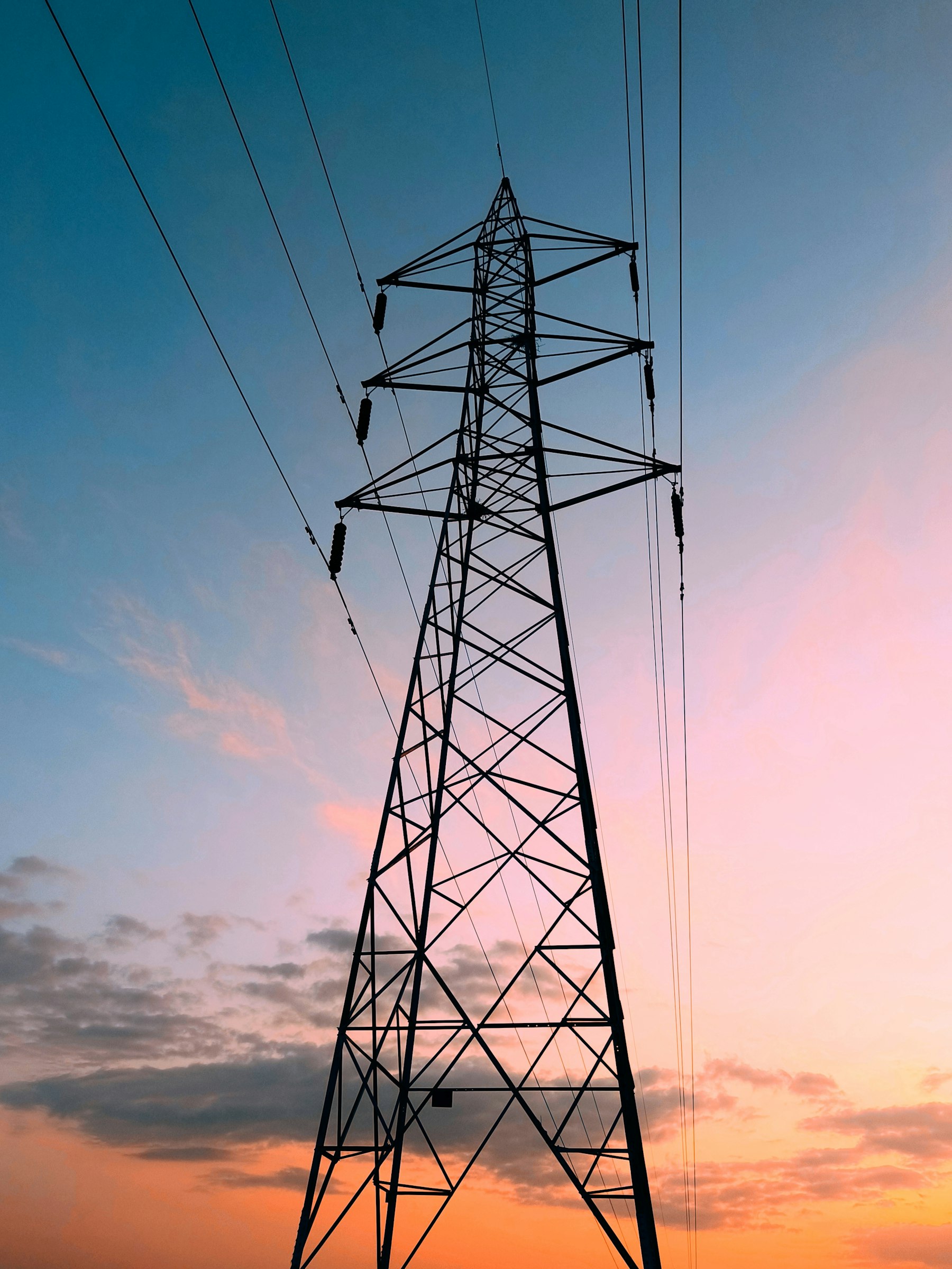 High-voltage transmission tower against a warm sunset sky