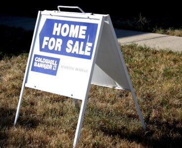 A home for sale sign on a lawn representing a house purchase before appraisal