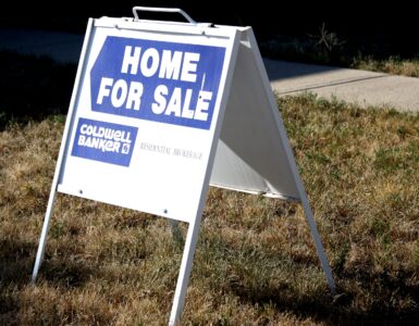 A home for sale sign on a lawn representing a house purchase before appraisal