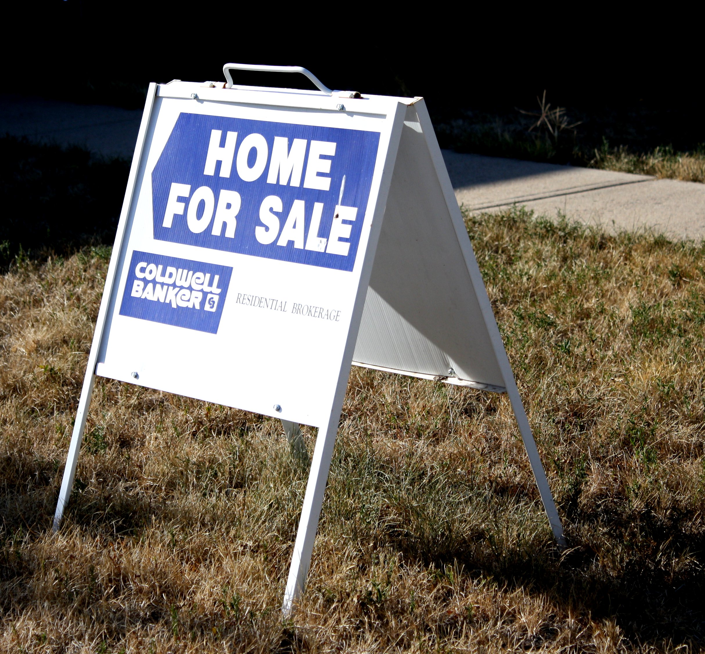 A home for sale sign on a lawn before a buyer's appraisal and mortgage approval