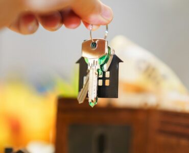 House keys, money, and a wallet representing insurance costs and household risk decisions