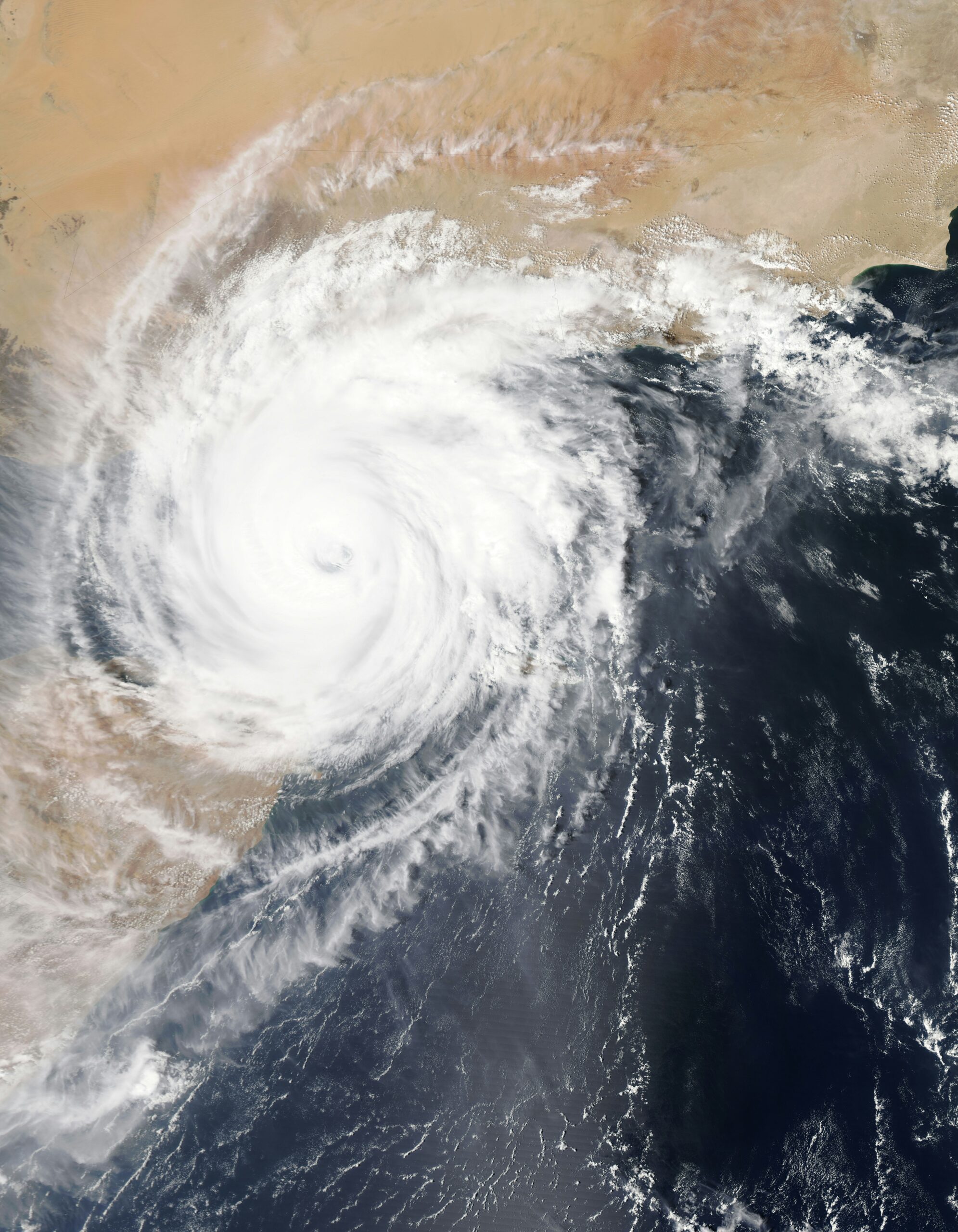 Satellite view of a tropical cyclone swirling near dry desert land