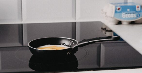A frying pan sits on a black induction cooktop in a modern kitchen