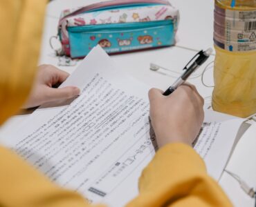 A learner studies Japanese text with notes and colorful stationery on a desk.