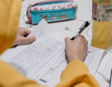 A learner studies Japanese text with notes and colorful stationery on a desk.