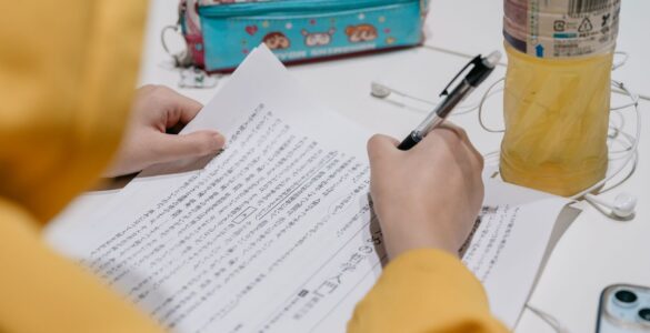 A learner studies Japanese text with notes and colorful stationery on a desk.