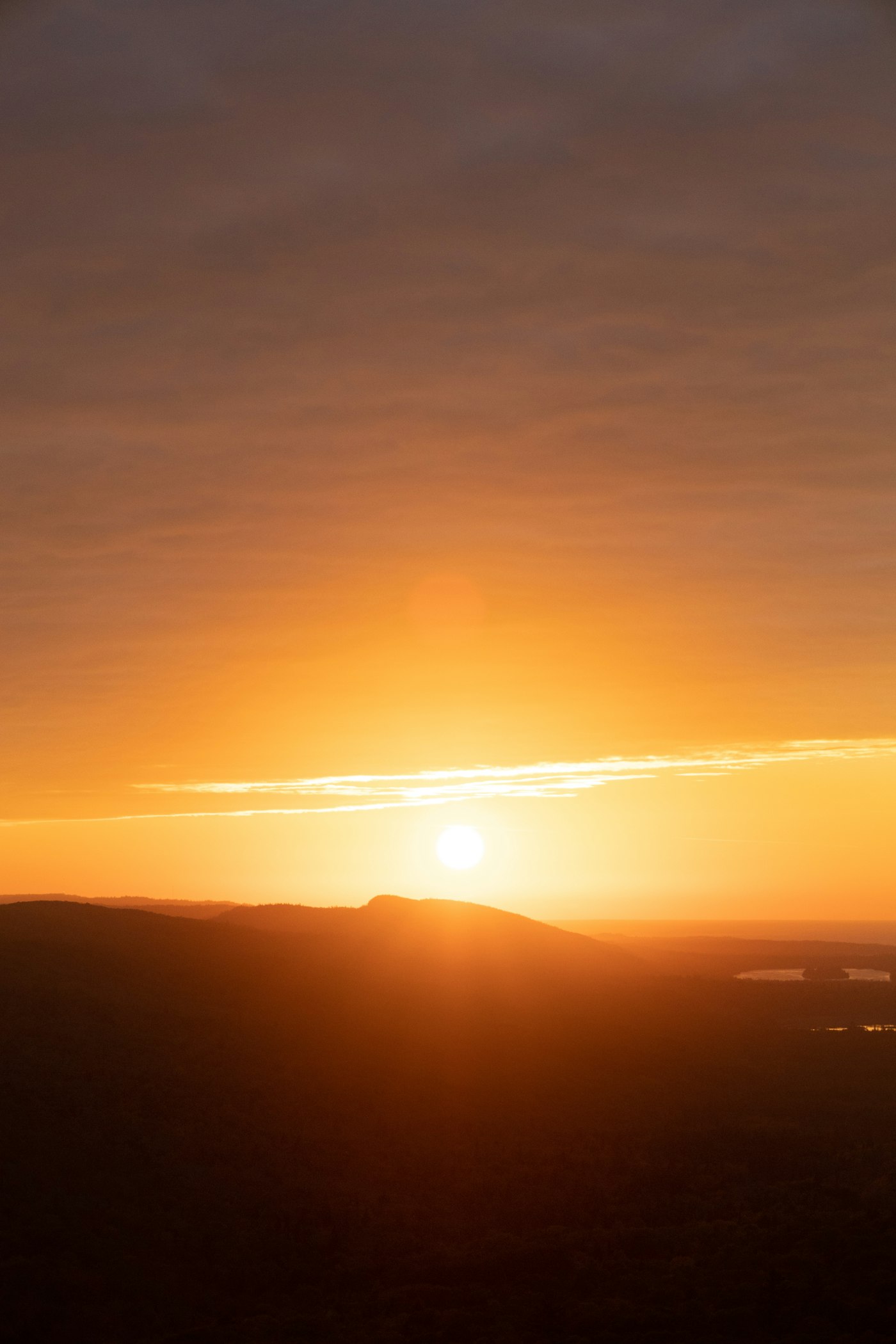 The Sun glowing low above hills near the end of the day