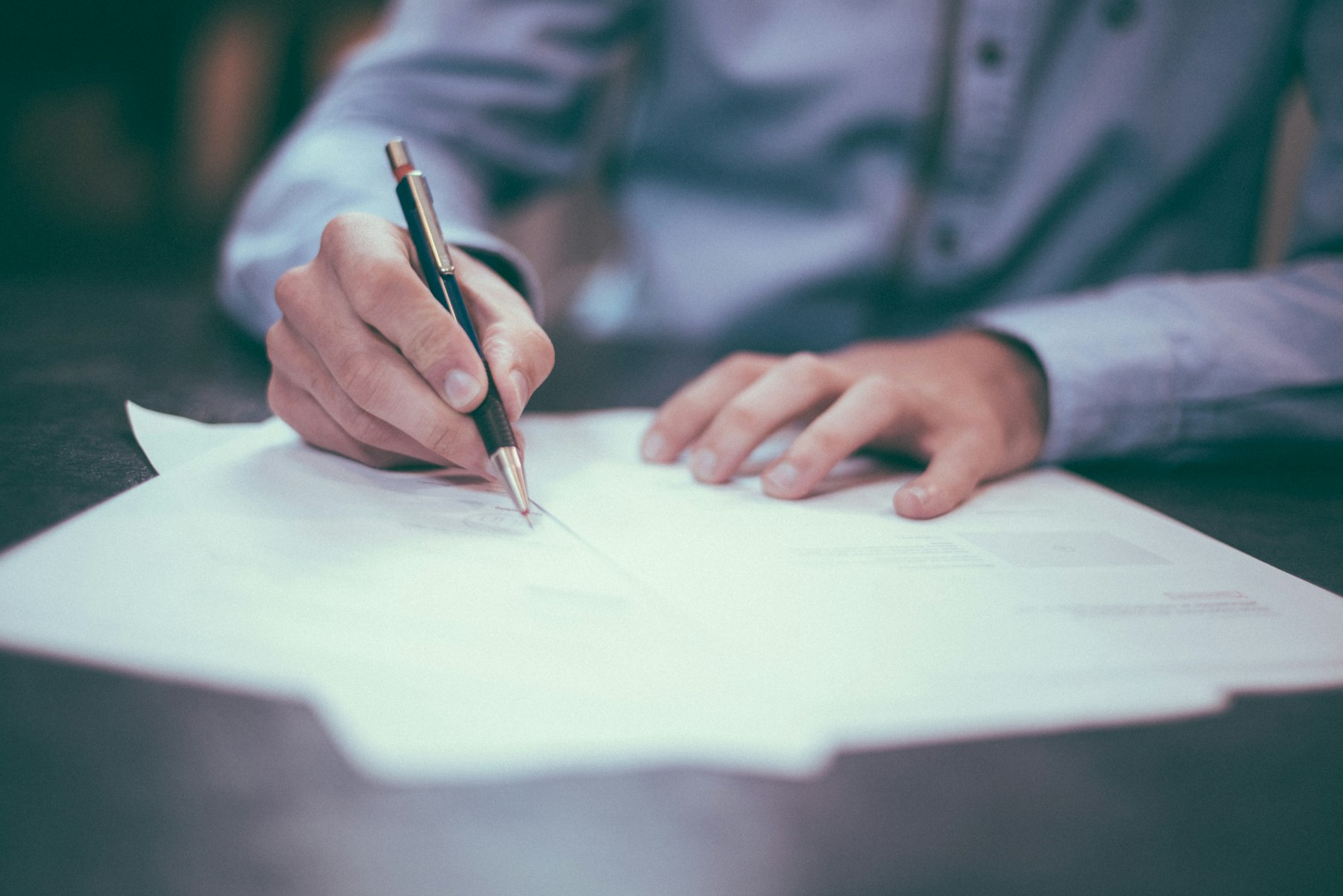 A person signing loan documents, representing the difference between rate and APR.