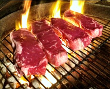 Steaks browning on a hot grill as high heat creates a flavorful crust