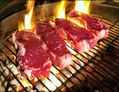 Steaks browning on a hot grill as high heat creates a flavorful crust
