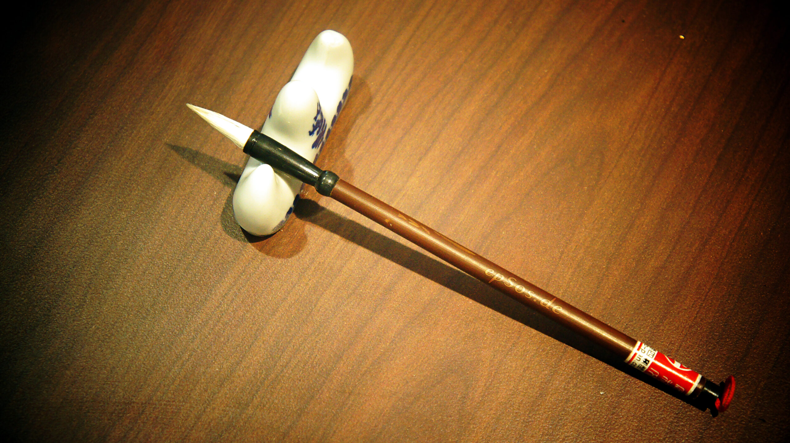 A Chinese calligraphy brush beside paper, suggesting careful attention to Mandarin characters and sentence endings.