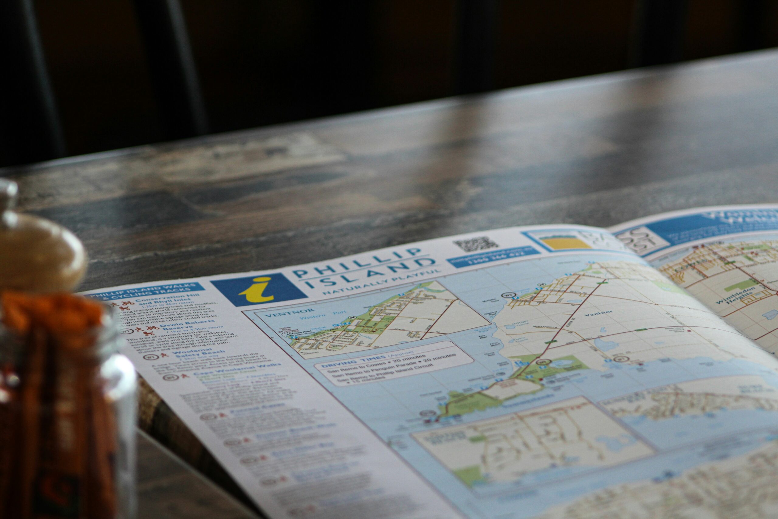 A folded map and brochure on a wooden table suggest route planning.