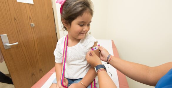 A child looks at a bandage after receiving a vaccination at a clinic