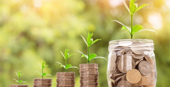 Coin stacks and a jar with small plants growing from them, symbolizing savings growth over time
