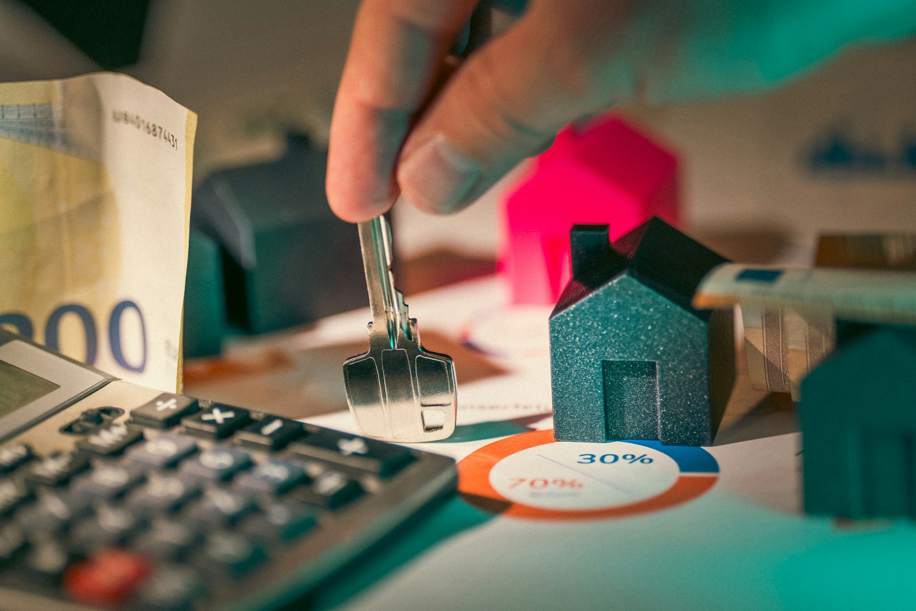 A calculator, keys, and house models used to compare mortgage costs.