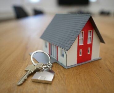 A model house and keys on a table representing mortgage costs and home buying.