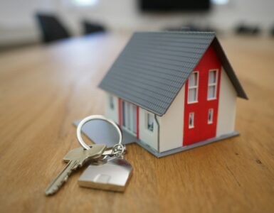 A model house and keys on a table representing mortgage costs and home buying.