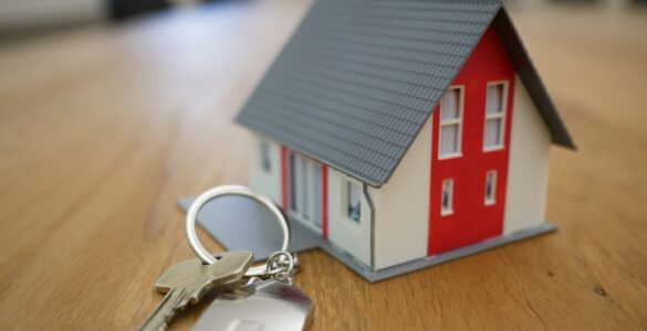 A model house and keys on a table representing mortgage costs and home buying.