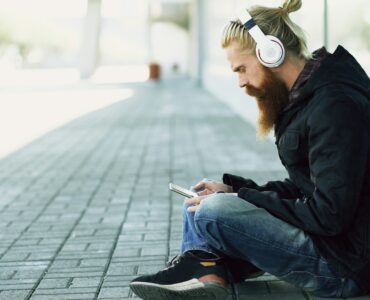 Person wearing headphones while listening to music on a smartphone