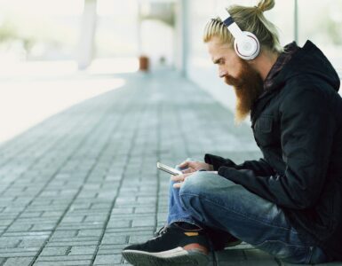 Person wearing headphones while listening to music on a smartphone