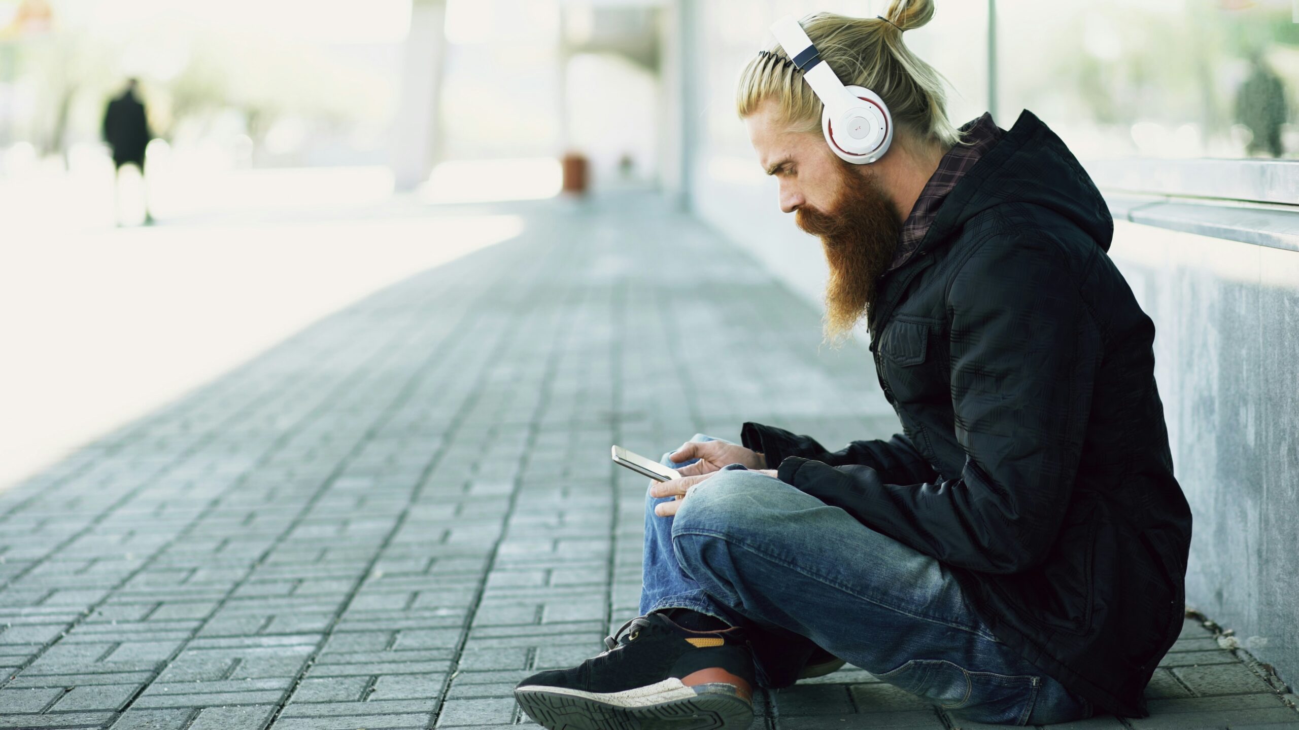 Person wearing headphones while listening to music on a smartphone
