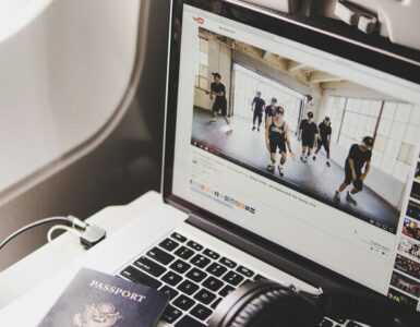 Headphones beside a laptop and passport on an airplane tray table