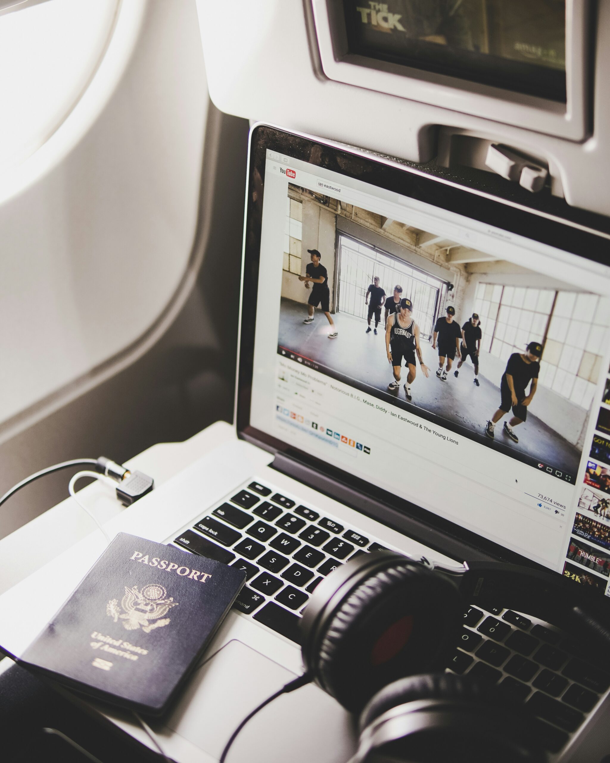 Headphones, laptop, and passport on an airplane tray table during air travel