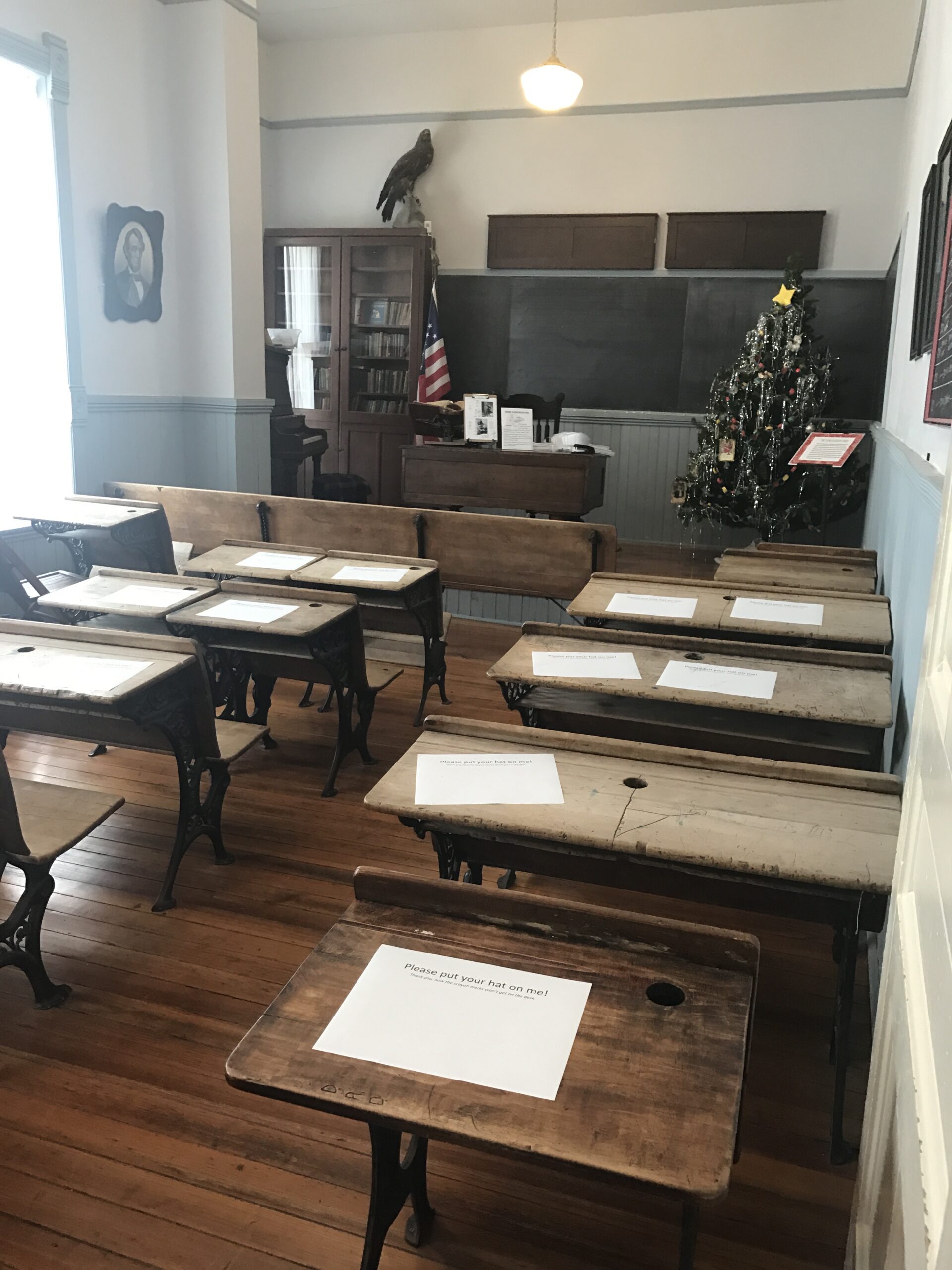 A one-room schoolhouse classroom with wooden desks and a chalkboard