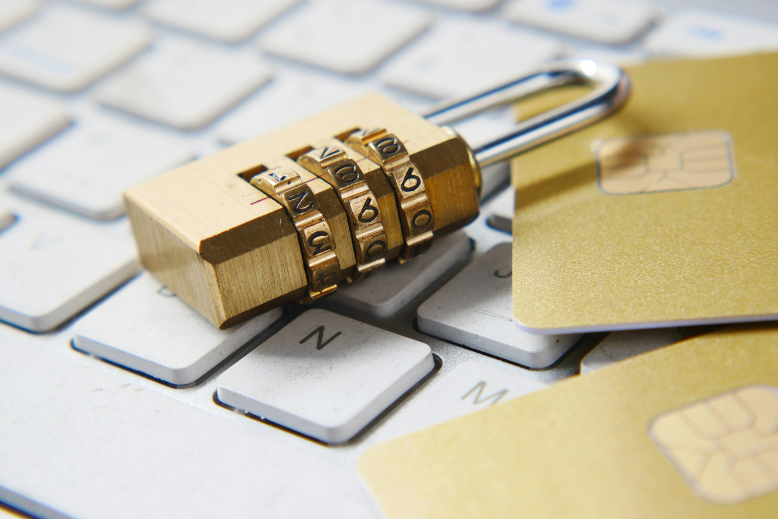 A combination lock resting on a computer keyboard beside payment cards.