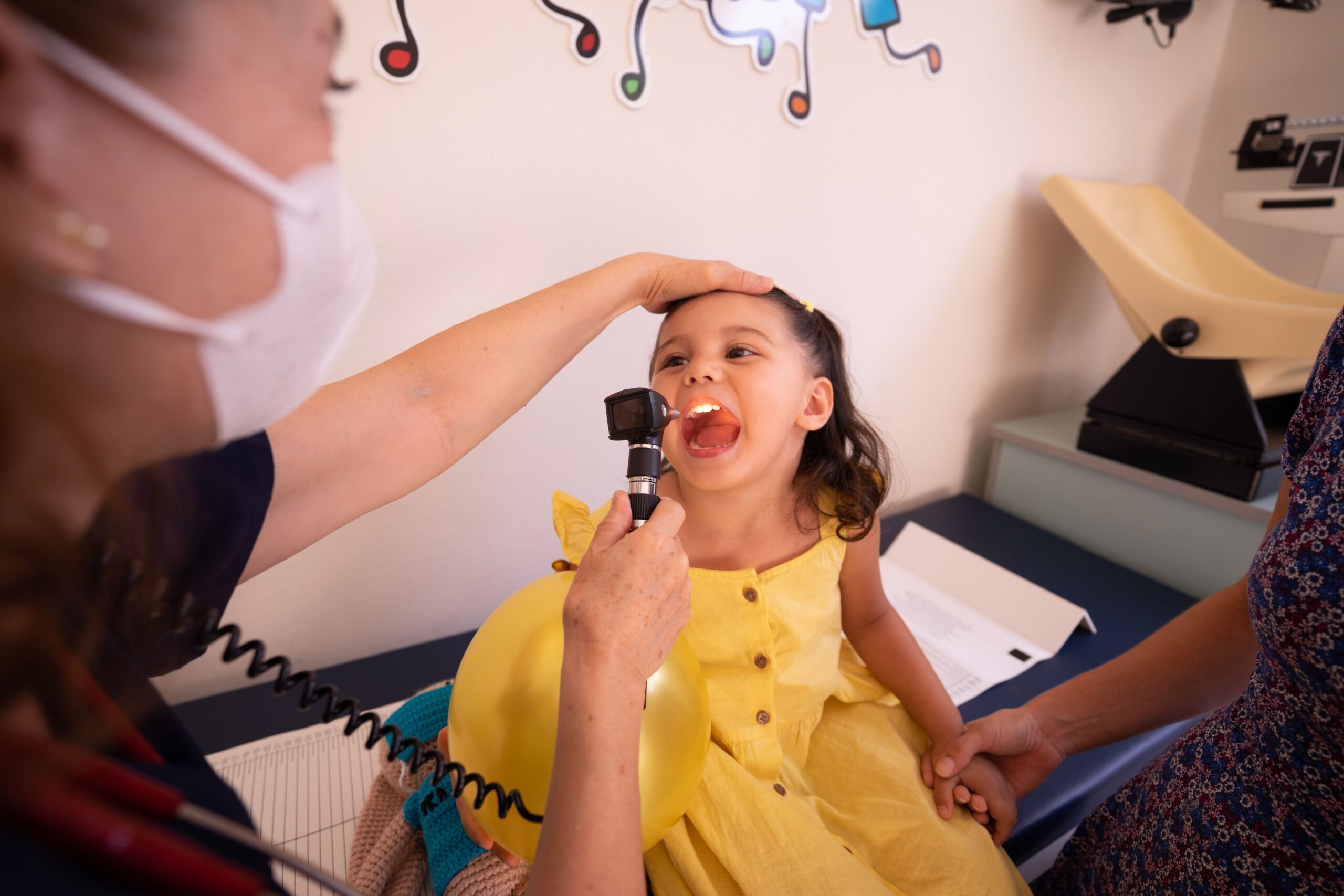 A clinician checks a young child's throat during a pediatric visit