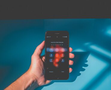 A hand holding a smartphone with a passcode screen for account security