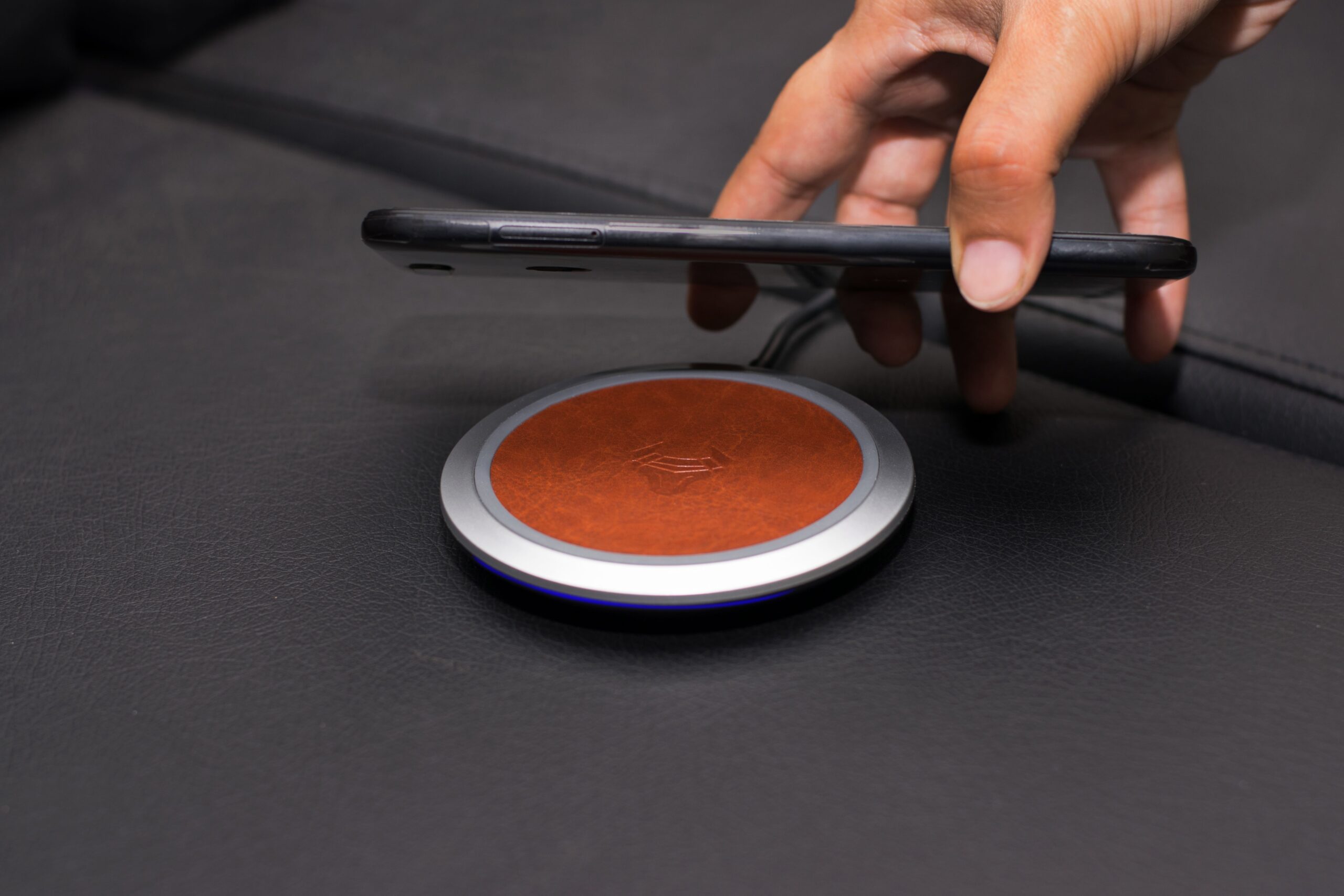 A hand placing a smartphone onto a wireless charging pad