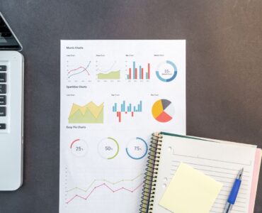 Printed charts and a laptop on a desk for comparing survey data