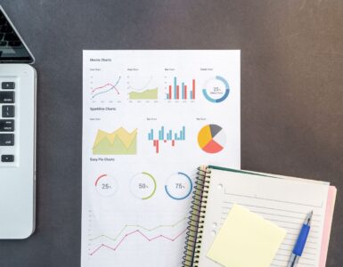 Printed charts and a laptop on a desk for comparing survey data