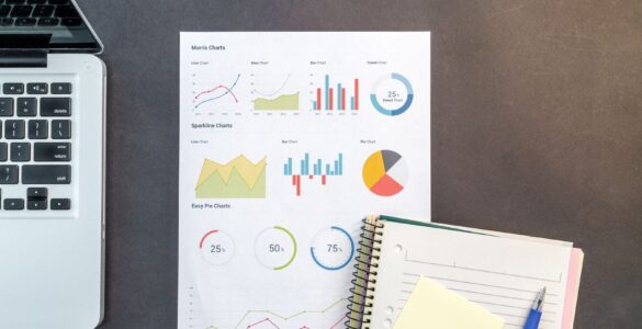 Printed charts and a laptop on a desk for comparing survey data