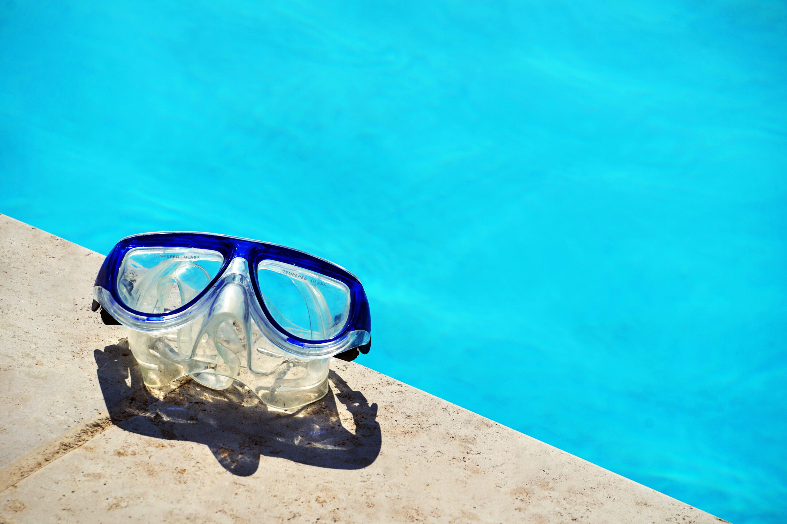 Swimming goggles resting near the edge of a pool