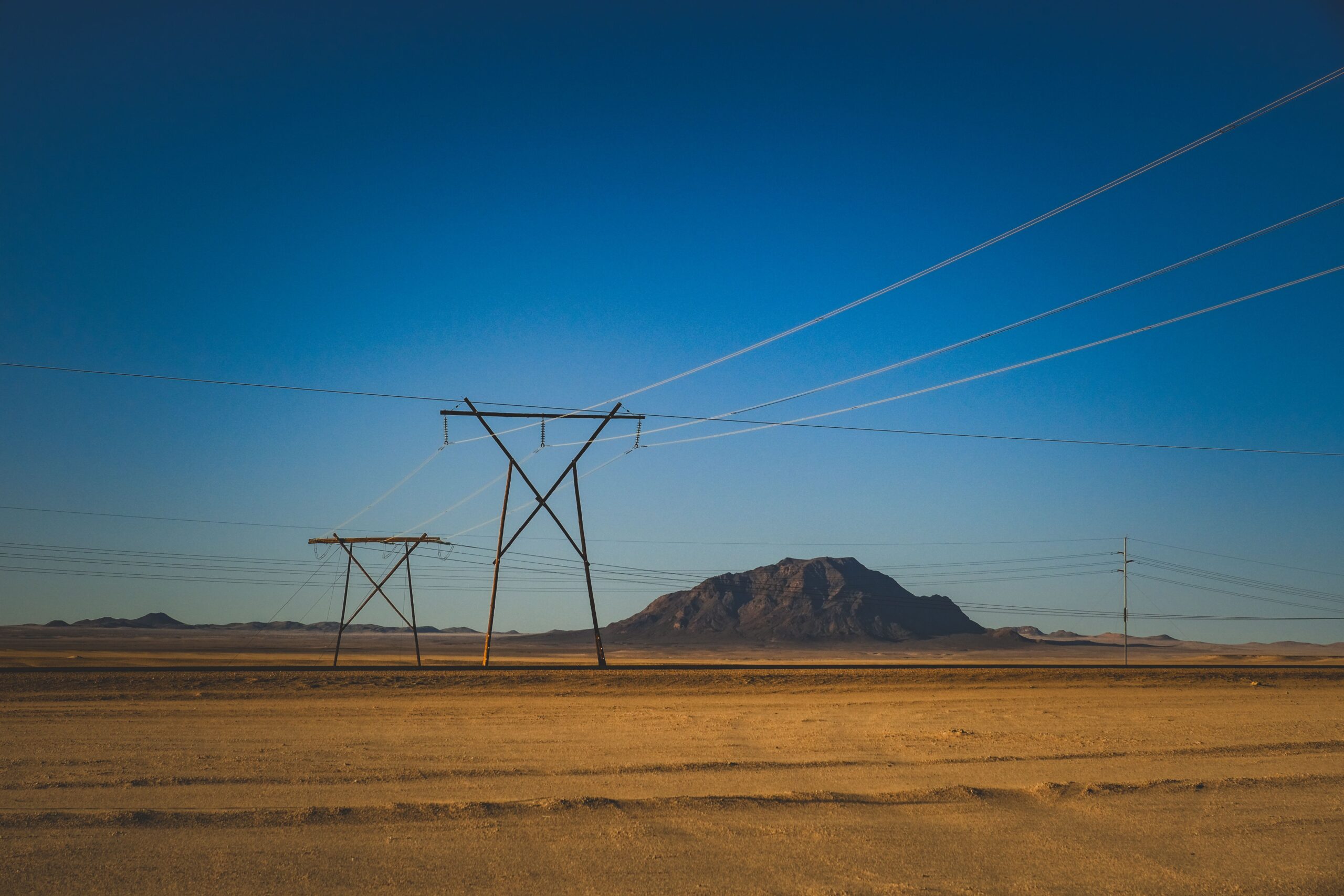 High voltage power lines crossing a dry landscape under a clear sky