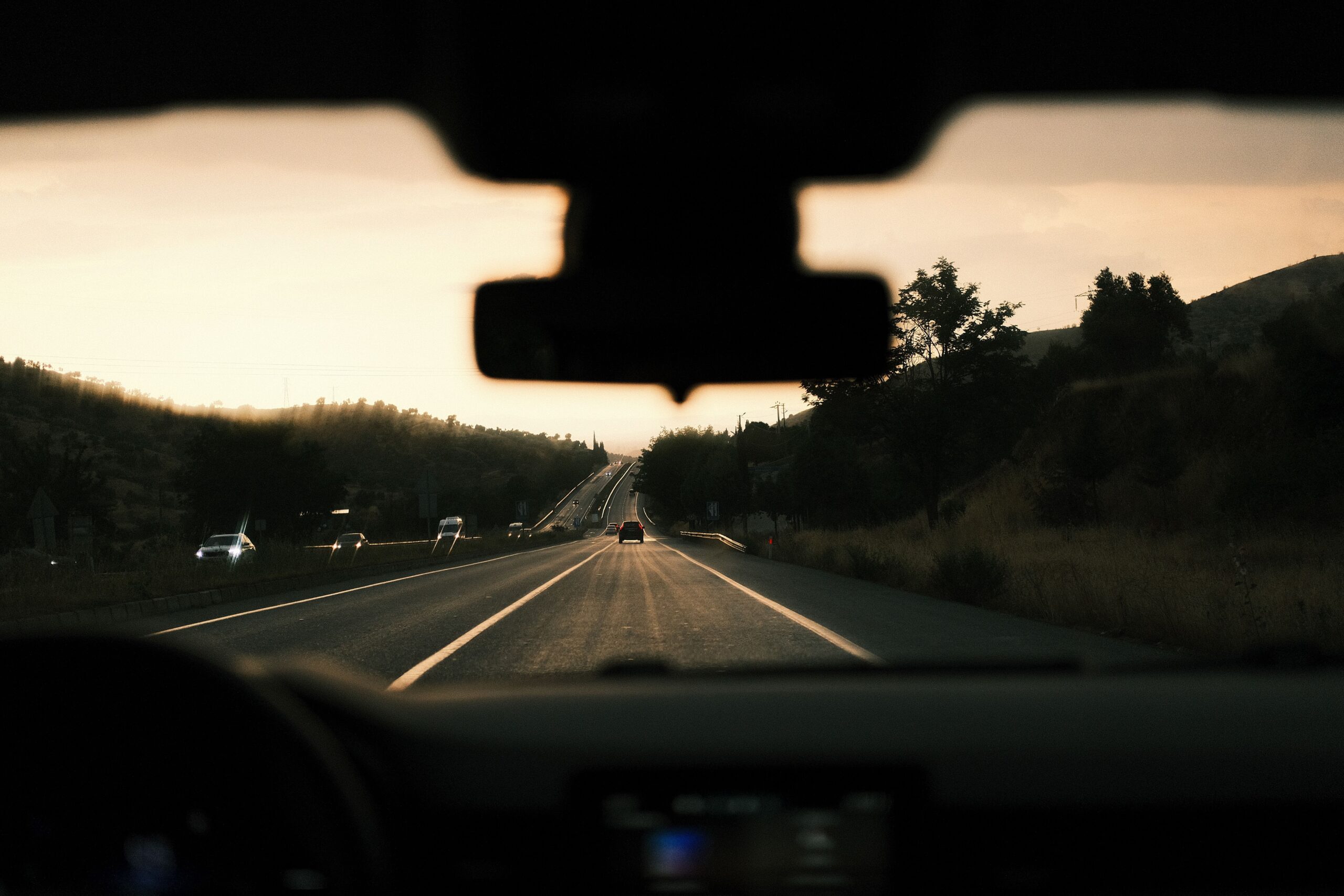A road seen through a car windshield in evening light