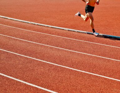 A runner on a sunny outdoor track, where heat and humidity can change safe exercise conditions.