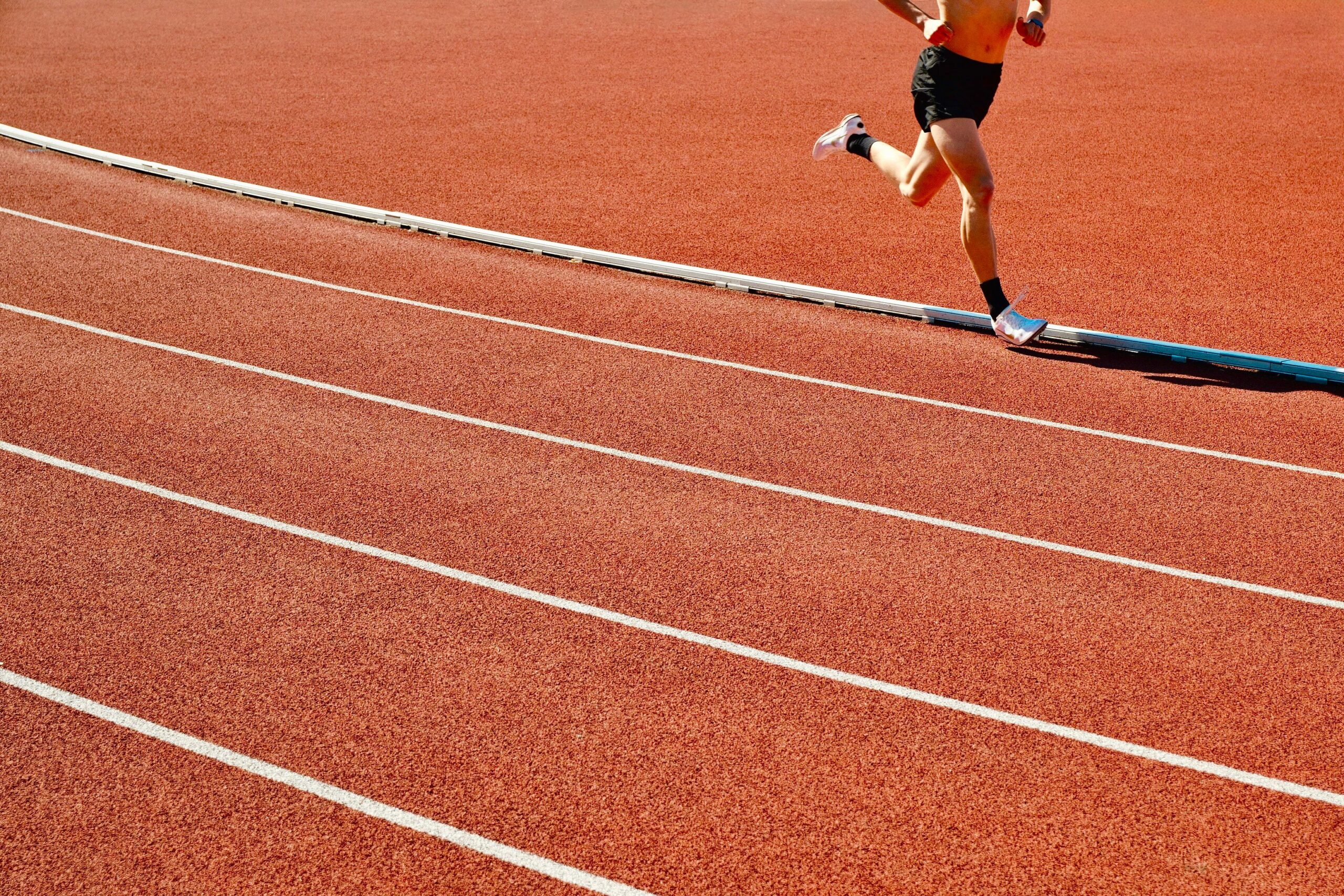 A runner on a sunny outdoor track, where heat and humidity can change safe exercise conditions.