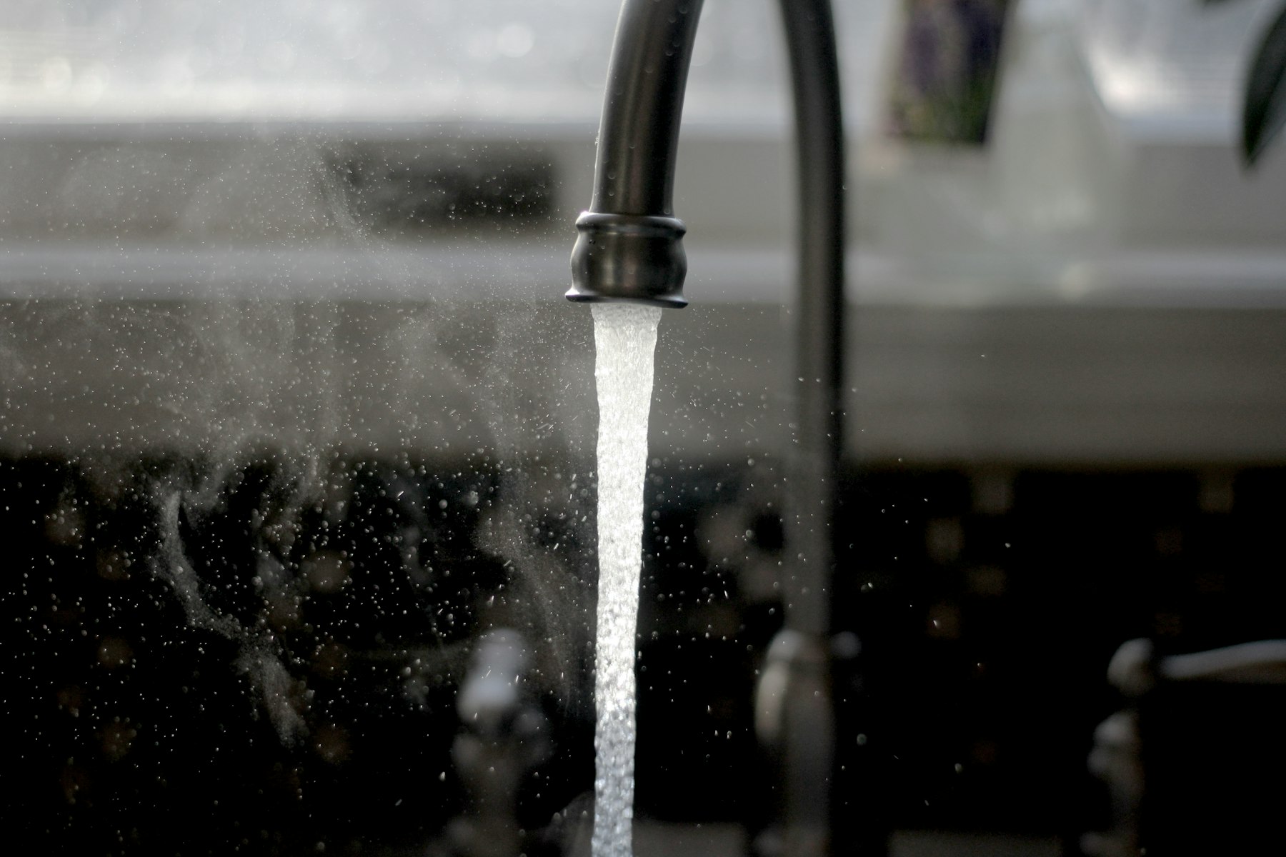 Clear water flows from a kitchen faucet into a sink