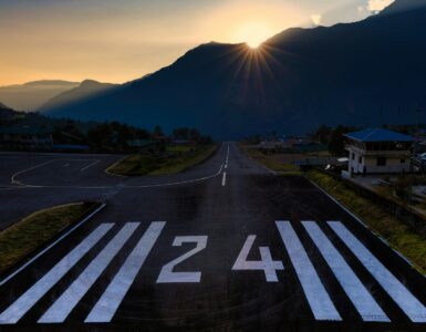Runway number 24 painted on an airport runway with mountains in the background