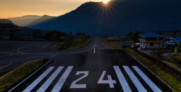 Runway number 24 painted on an airport runway with mountains in the background