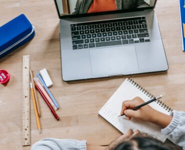 A student organizing papers and notes beside a laptop