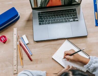 A student organizing papers and notes beside a laptop