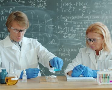 Students in lab coats conducting a classroom experiment with beakers and test tubes.